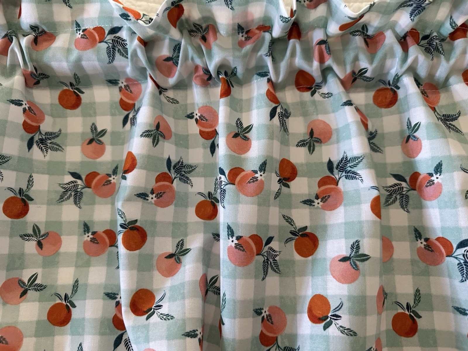 Small Checked Valance With Peaches. The Background Is A Green Blue Color. New