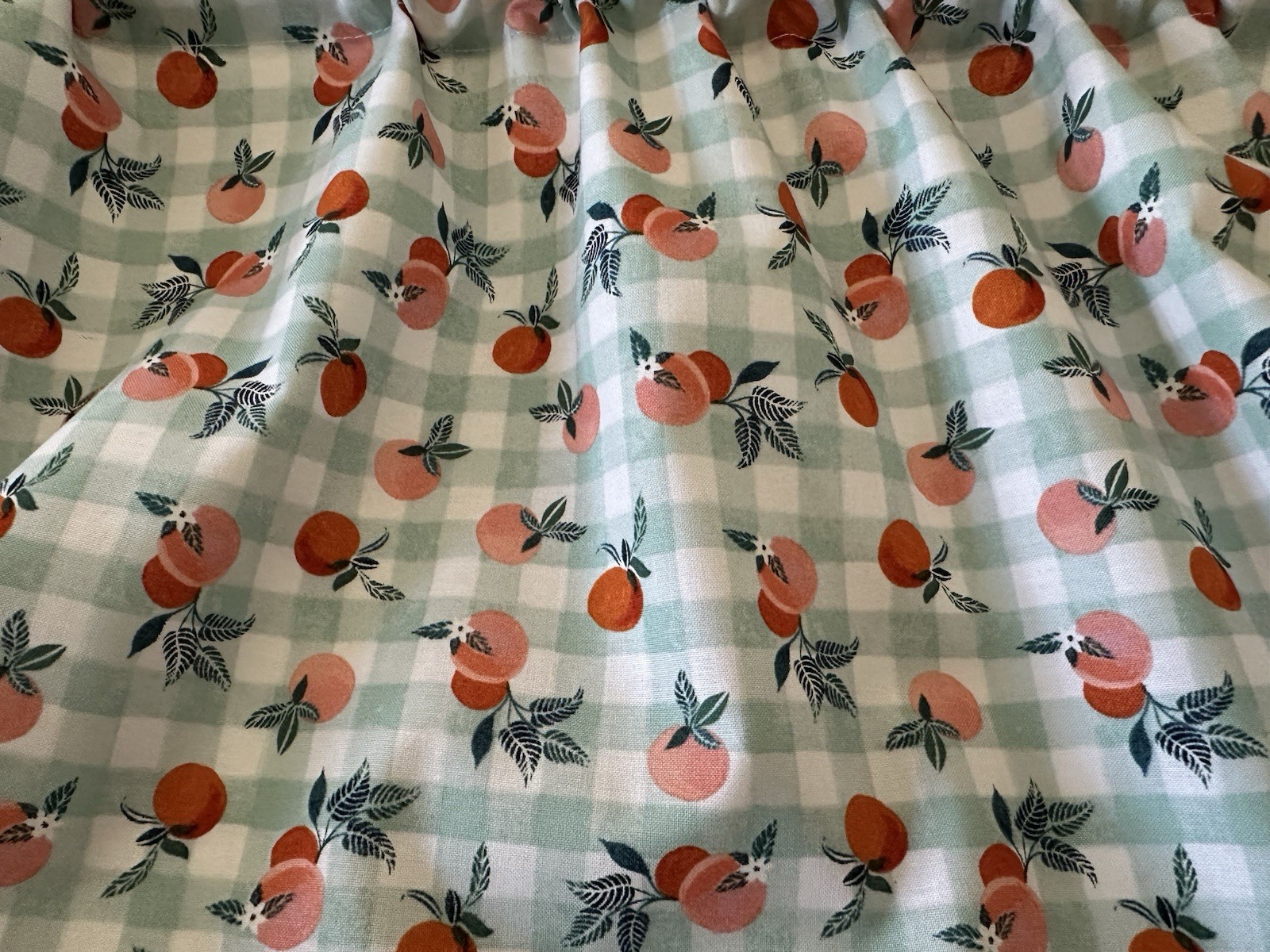 Small Checked Valance With Peaches. The Background Is A Green Blue Color. New